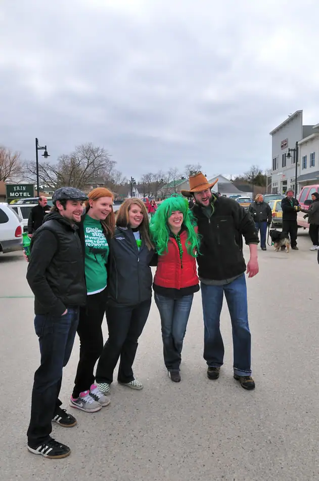 Five people in festive clothing pose on a street beneath an overcast sky.