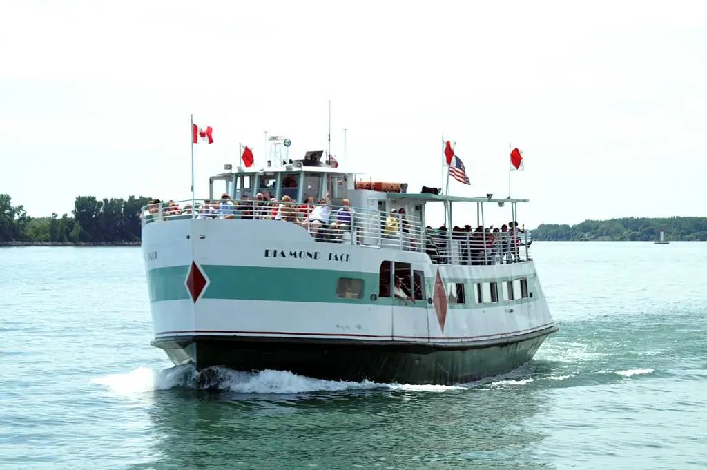 A passenger ferry named DIAMOND JACK carries people past a wooded shoreline.