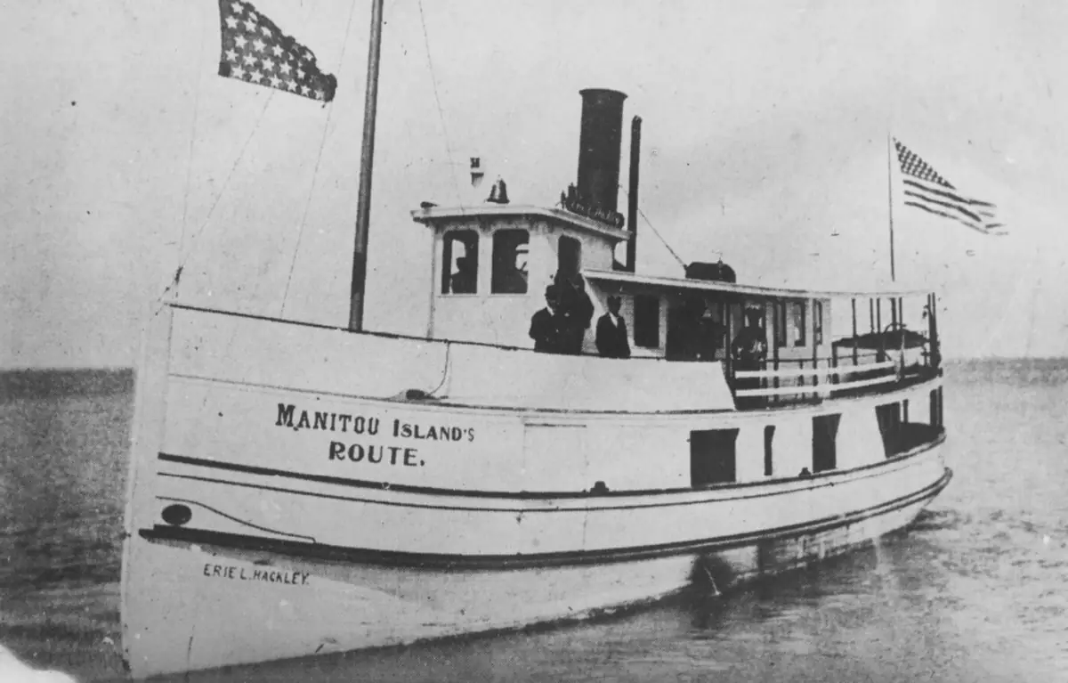 The steamer Erie L. Hackley, bow-on, flying the U.S. flag, her hull lettered ERIE L. HACKLEY and cabin banner reading MANITOU ISLAND'S ROUTE.