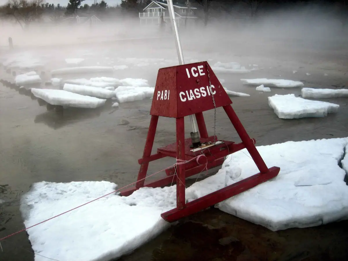 A red wooden frame marked “PABI ICE CLASSIC” stands among broken ice on misty water.