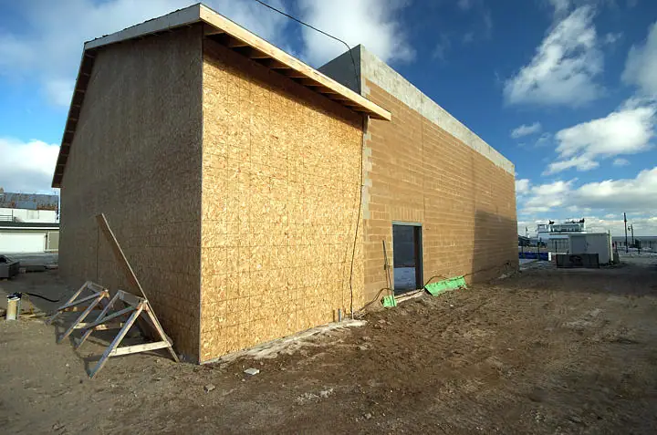 Partially built structure with OSB sheathing, concrete-block walls, and exposed roof framing.