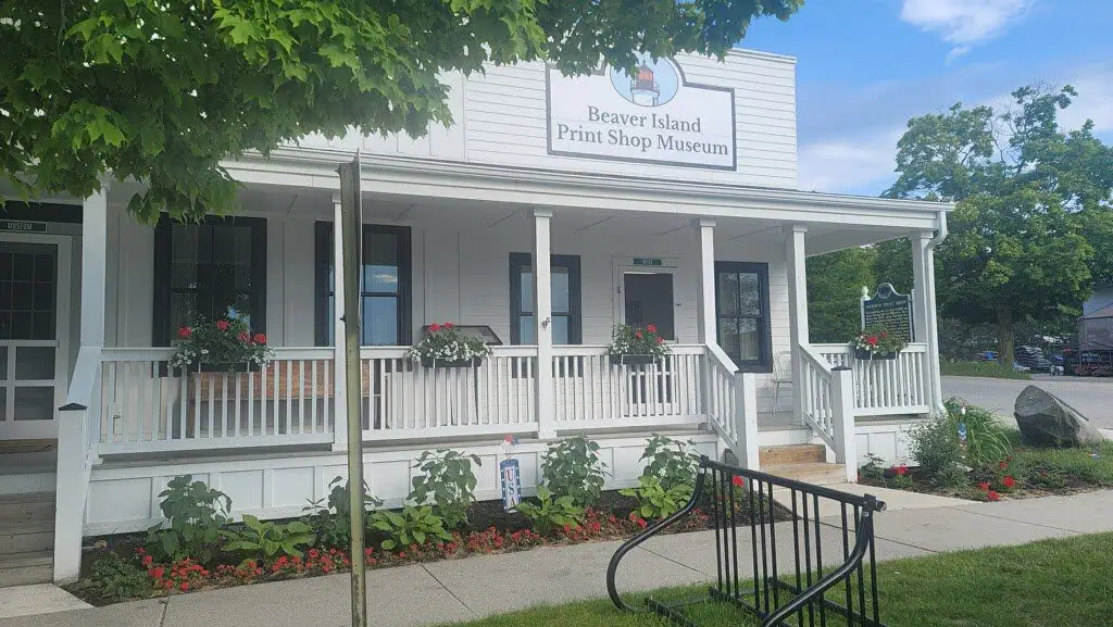 White clapboard building with a covered porch, flower boxes, and a large sign above the entrance.