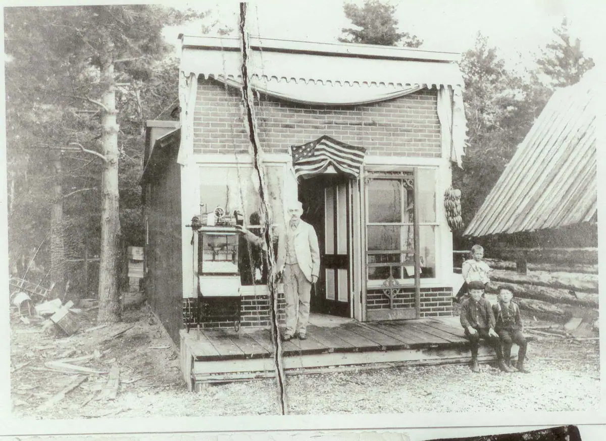 Black-and-white photograph of a man and three children outside a brick storefront.
